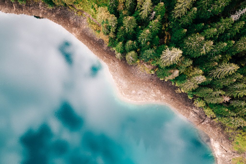 Drohnenfoto von einem blauen See mit Bäumen am Rand